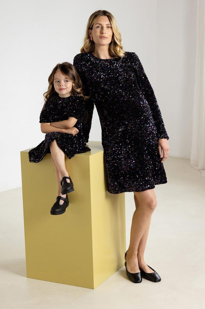 Schwangere Mama im Paillettenkleid neben ihrer Tochter im gleichen Kleid im Mini-Style