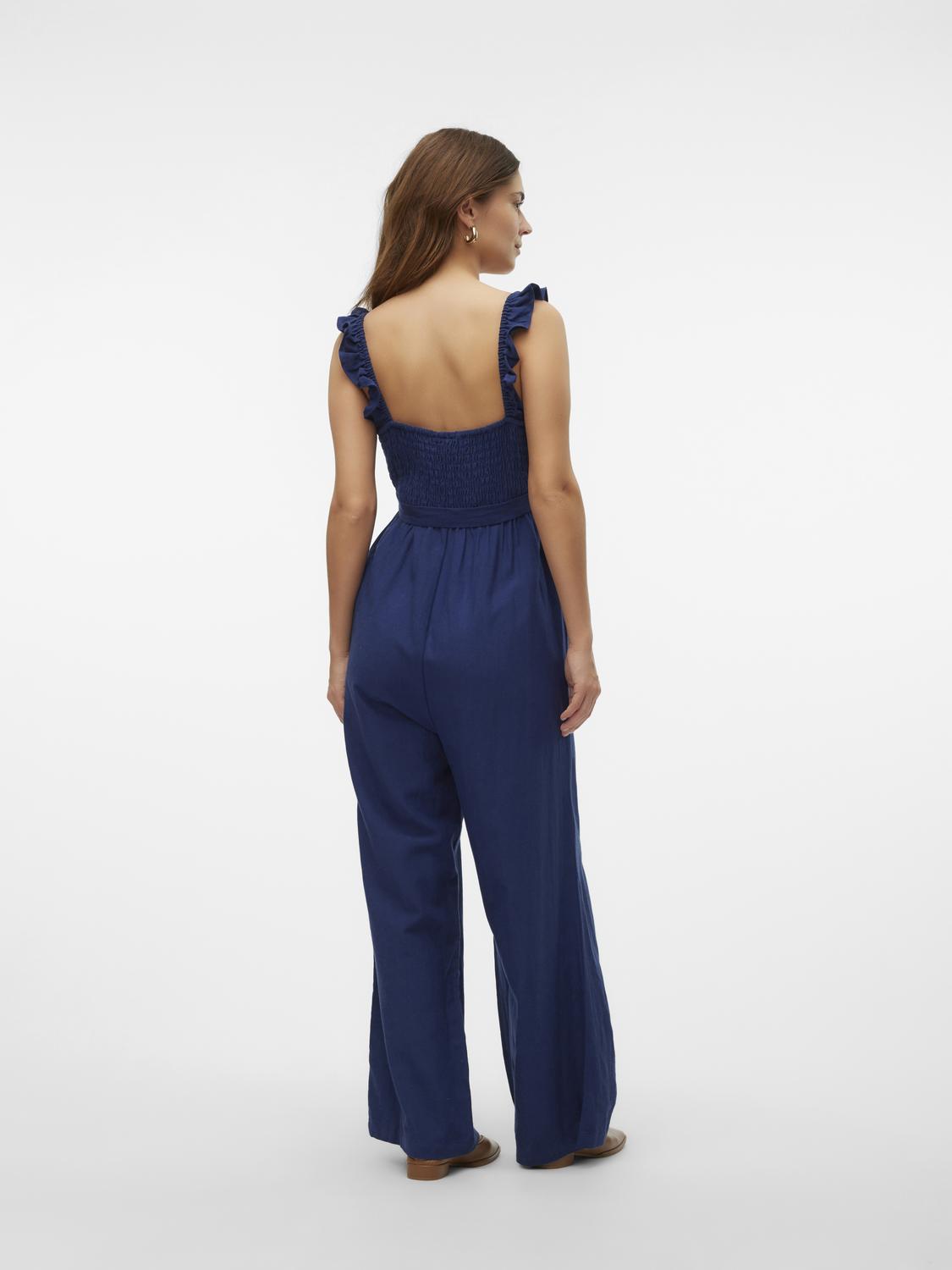 Model zeigt Rückseite des Mamalicious Jumpsuits, tiefer Rückenausschnitt. Bei Mutterkleid kaufen oder mieten.