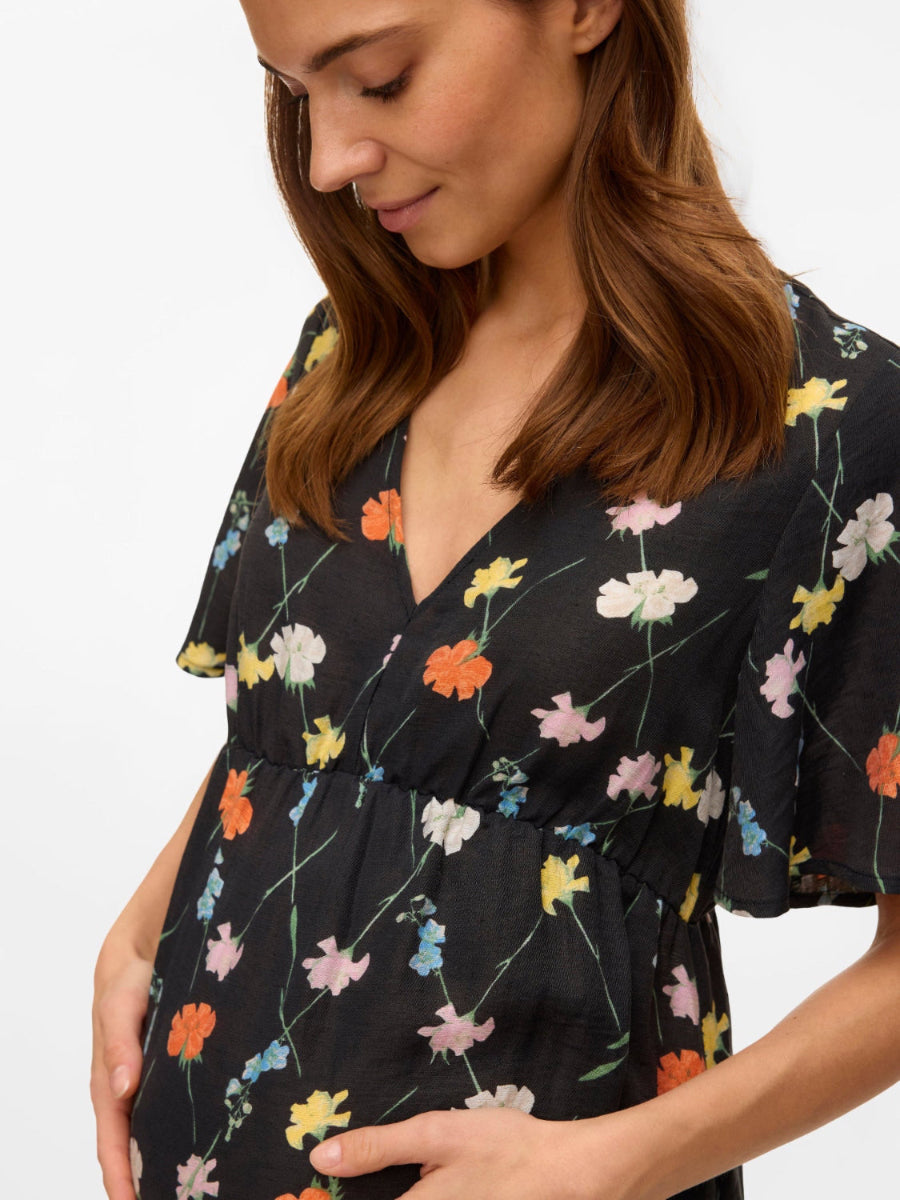 Schwangere Frau mit Blumenkleid. Kaufe oder miete Umstandskleider bei Mutterkleid