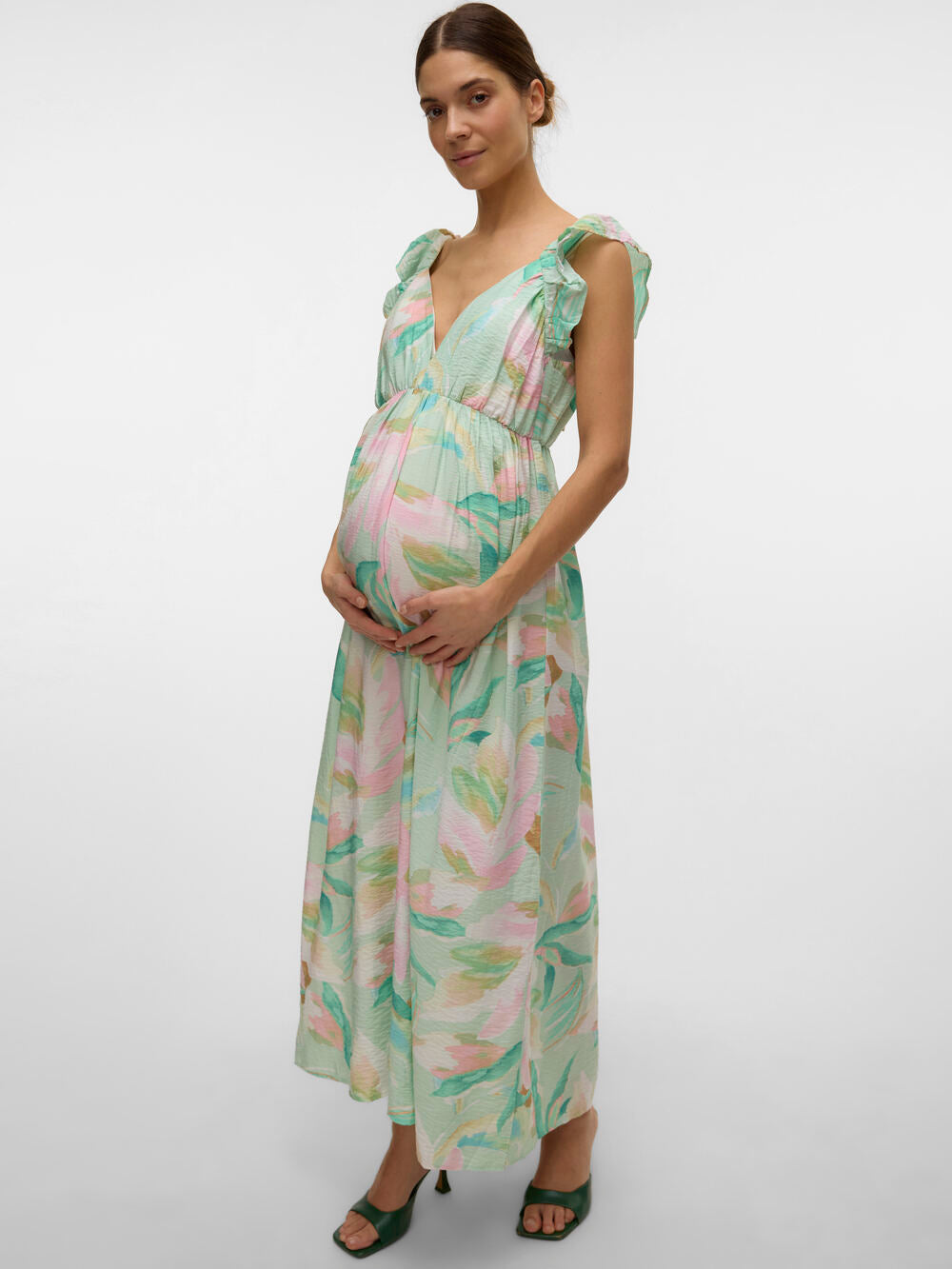 Model zeigt seitlich das Maxikleid Umstandskleid in Pastellfarben mit grünen Heels. Kleid bei Mutterkleid erhalten.