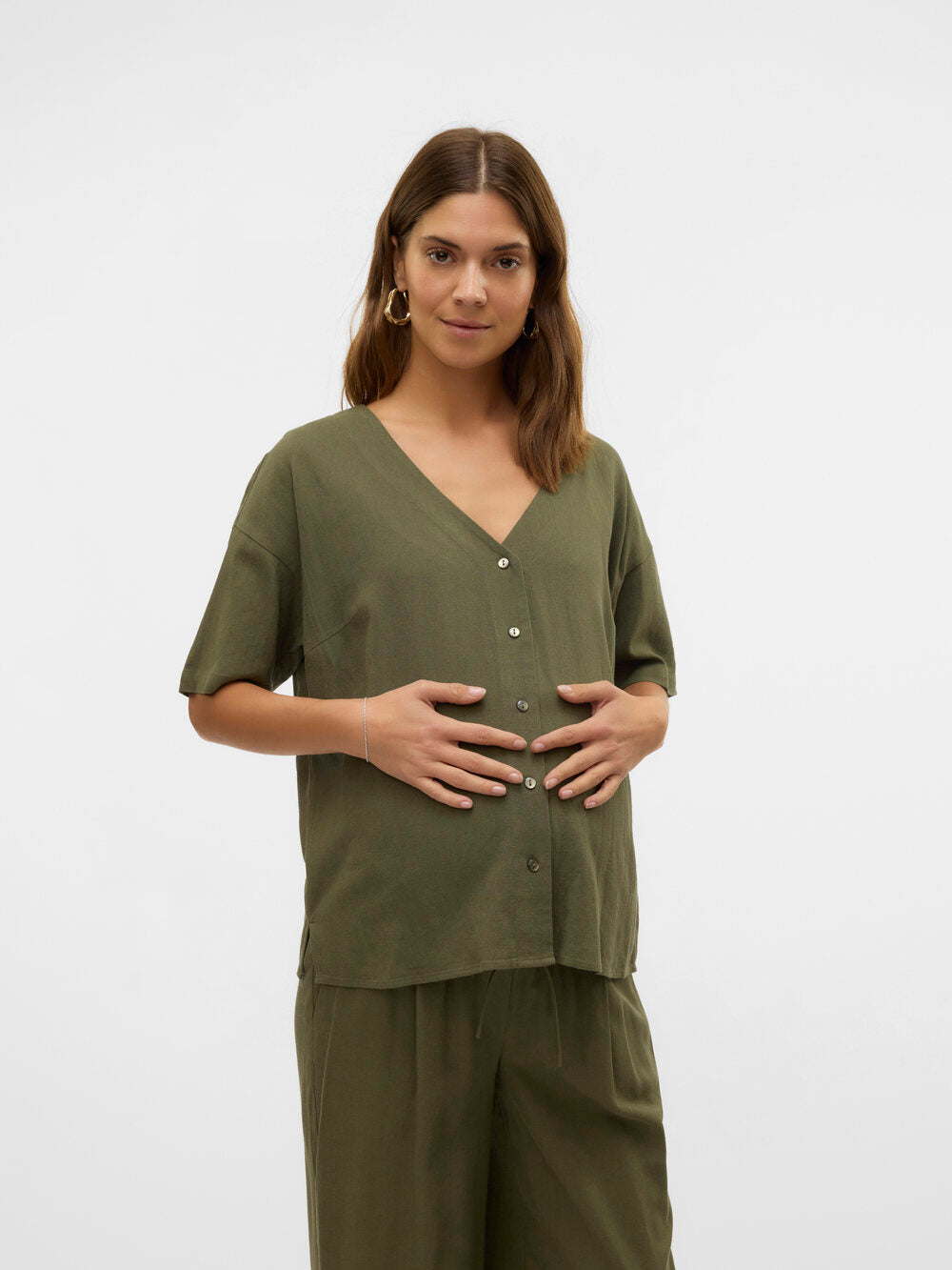 Model zeigt die grüne Umstandsbluse Stillbluse von Vero Moda Maternity von vorne mit Händen auf dem Bauch. Bluse bei Mutterkleid.de kaufen oder mieten