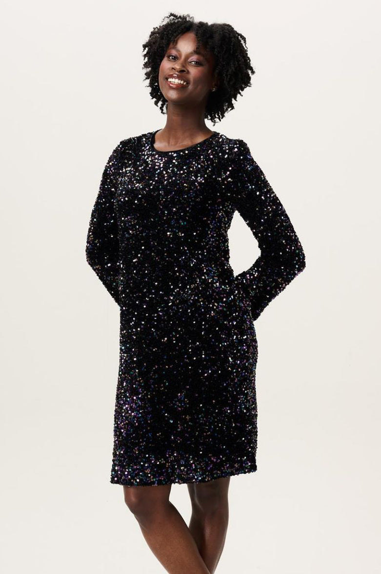 Model im Profil mit Paillettenkleid für die Schwangerschaft mit langem Arm und Rundhalsausschnitt in Knielänge