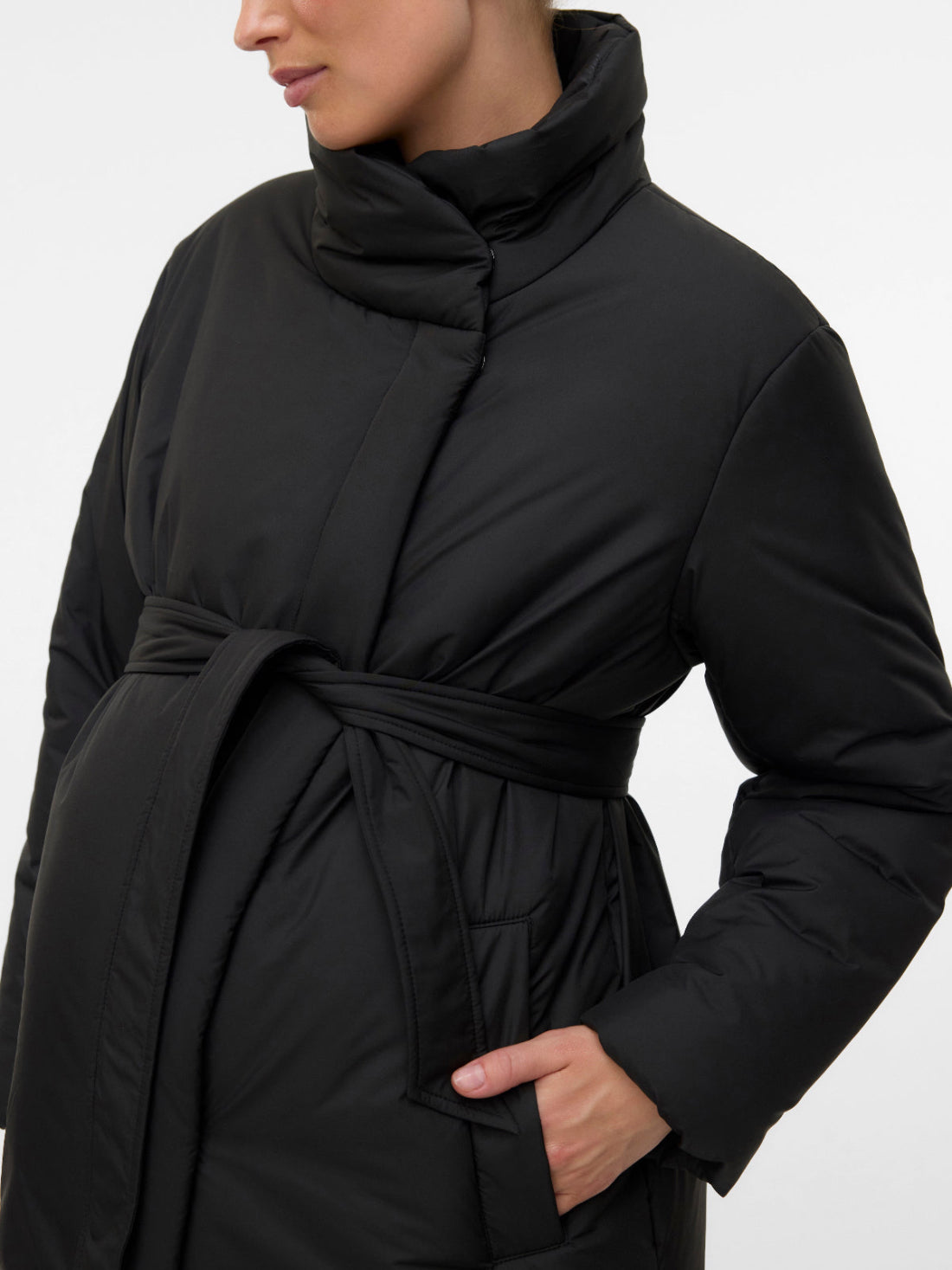 Detailaufnahme Stehkragen, Stoff, Gürtel und Eingriffstaschen des schwarzen Mamalicious Umstandsmantels für die Schwangerschaft