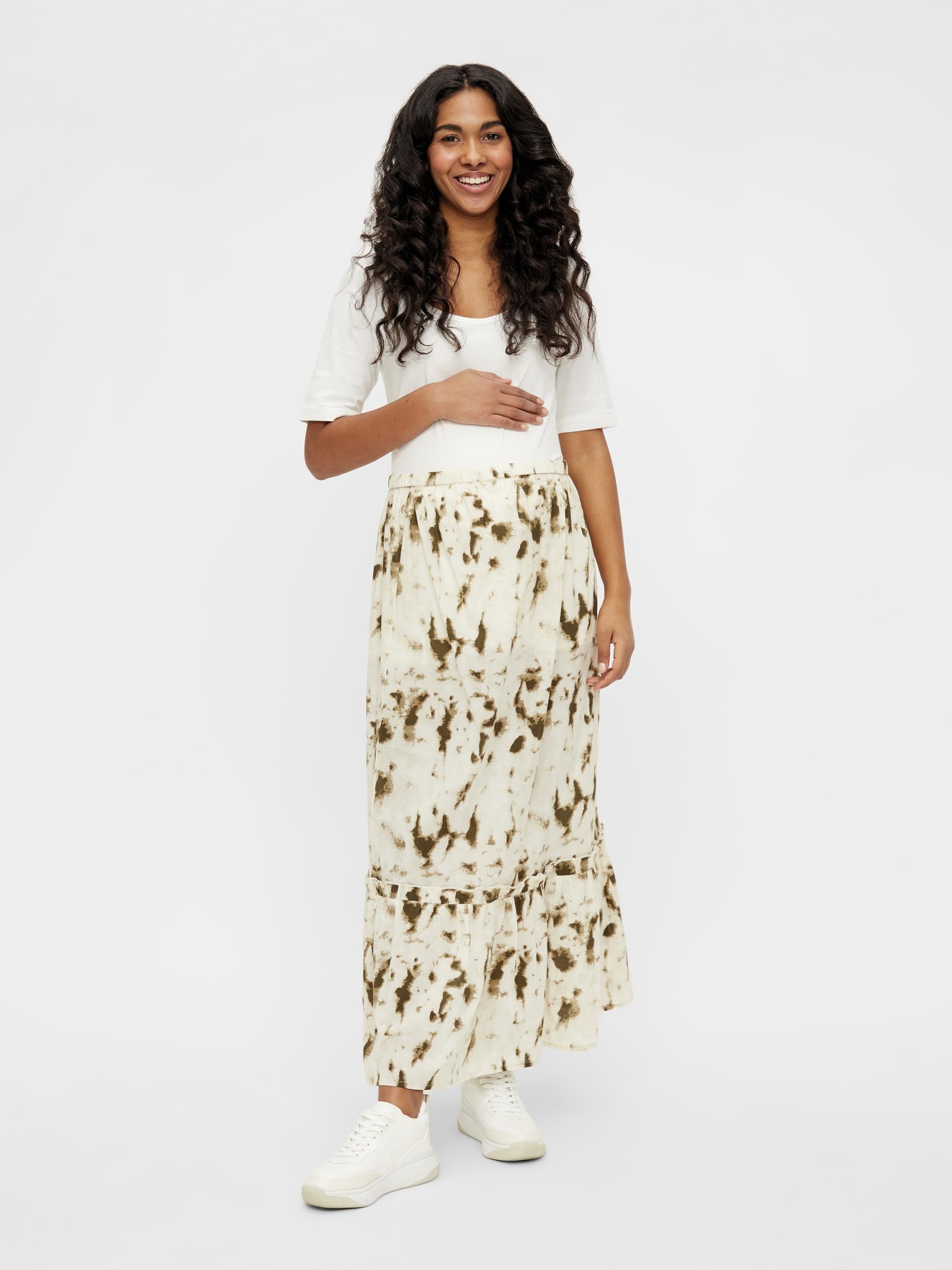 Im Mutterkleid Online Shop: dunkelhaariges lachendes Model zeigt Mamalicious Maxi Rock Batikoptik Tie-Dye-Muster Umstandsrock von vorne. Jetzt kaufen oder mieten